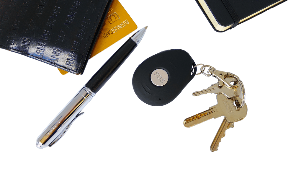 Conjunto de objetos entre os quais uma botoneira, chaves, caneta, carteira, cartão e um bloco